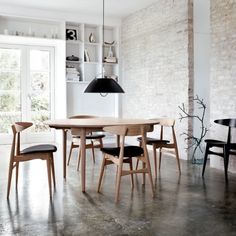 a dining room table and chairs in front of a brick wall with an open window