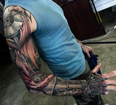 a man with a tattoo on his arm and hand holding something in the other hand