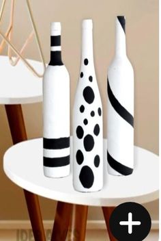 three wine bottles sitting on top of a white table next to a potted plant