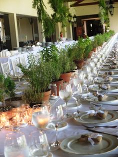 a long table is set with plates, glasses and candles for an elegant dinner party