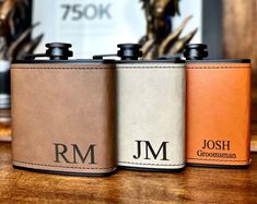 three personalized flasks sitting on top of a wooden table