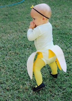 a baby dressed as a banana is standing in the grass with its hand on his face