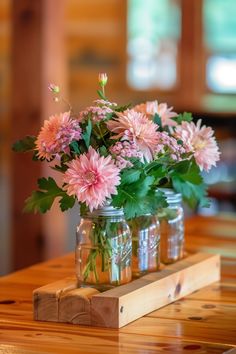 pink flowers are in mason jars on a wooden table