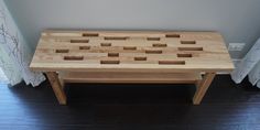 a wooden coffee table with squares on it in front of a curtained room window