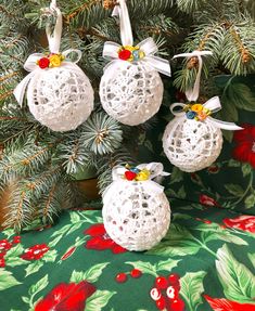 three white crocheted ornaments hanging from a christmas tree