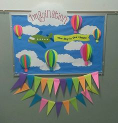 the bulletin board is decorated with hot air balloons and paper banners that read,'congratulations the sky is the limit '