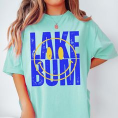 Hey there, Lake Bum! Are you ready to soak up the sun and embrace the laid-back vibes of lakeside living? Introducing our "Lake Bum" Comfort Color Tee – the perfect blend of relaxation and waterfront charm! Crafted from premium Comfort Color fabric, this tee feels as soft as a gentle breeze off the water. The playful "Lake Bum" graphic celebrates your love for lazy days by the lake, whether you're fishing off the dock or lounging in a hammock by the shore. Whether you're spending the day on a pontoon boat or simply enjoying a picnic by the water's edge, our tee is your go-to choice for casual comfort. Its relaxed fit ensures you stay cool and carefree, no matter where your lakeside adventures take you. From roasting marshmallows around the campfire to paddleboarding across the glassy surfa Graphic Print Top For Beach Season, Cotton Tops For Outdoor Beach Season, Summer Tops For Beach Season Outdoor, Lakeside Living, Roasting Marshmallows, Soak Up The Sun, Pontoon Boat, Lazy Days, Comfort Colors Tee