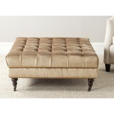 a beige ottoman sitting on top of a carpeted floor