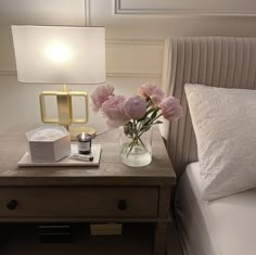 a bedside table with flowers in a vase on it