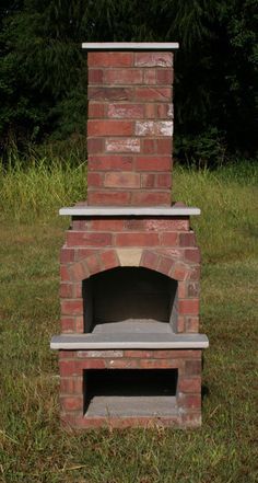 a brick oven sitting on top of a grass covered field