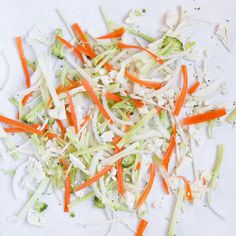 shredded carrots, broccoli and celery on a white surface