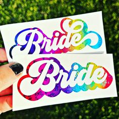 two stickers with the words bride and groom painted on them in rainbow colors are held by a hand