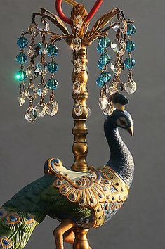 a peacock figurine is sitting on top of a lamp post with crystal beads