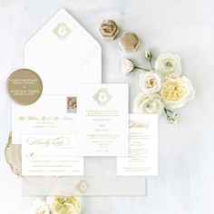 the wedding stationery is laid out on top of each other, with white flowers and gold foil