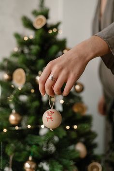 a person holding an ornament in front of a christmas tree