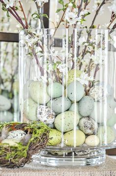 a vase filled with eggs sitting on top of a table next to a bird's nest