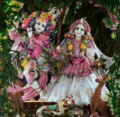 two women dressed in pink and white standing next to each other with flowers on their heads