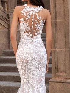 a woman in a white wedding dress standing on steps with her back to the camera