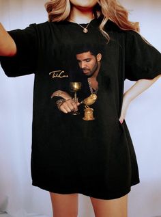 a woman wearing a black t - shirt with a photo of a man holding a golden bell