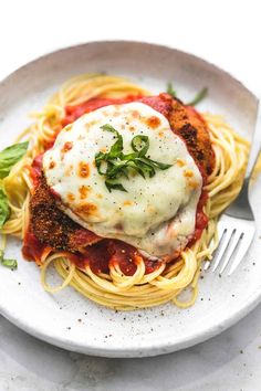 a white plate topped with spaghetti and meat covered in sauce on top of a table