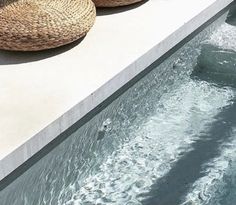 two woven baskets sitting on the edge of a swimming pool next to an open air hot tub