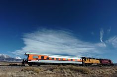 an orange and white train traveling through the desert