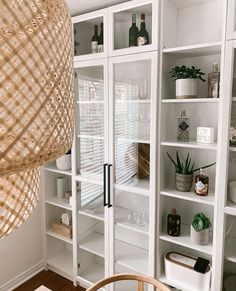 a room filled with lots of white bookshelves next to a dining room table