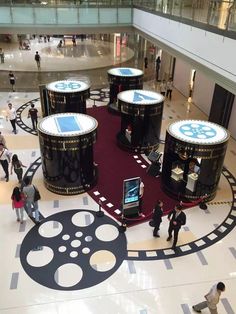 people are walking around in the lobby of a shopping mall with large black and white circles on the floor