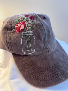 a hat with flowers in a mason jar embroidered on it