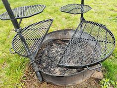 an outdoor fire pit with grills sitting on top of it's sides in the grass