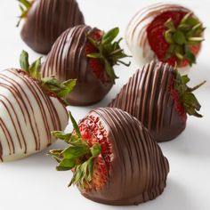 chocolate covered strawberries are arranged on a white surface