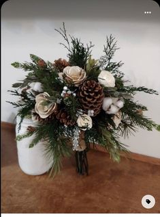 a white vase filled with flowers and pine cones