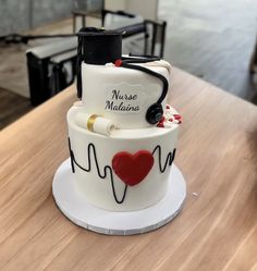 a three tiered cake decorated with medical equipment and writing on the side, sitting on top of a wooden table