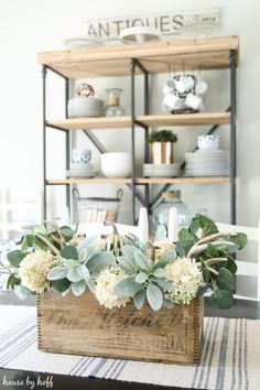 a wooden crate filled with white flowers and greenery on top of a striped rug