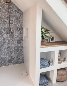 an attic bathroom with blue and white tiles on the shower wall, shelving unit