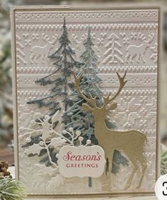 a christmas card with a deer standing next to a pine tree and the words season's greetings written on it