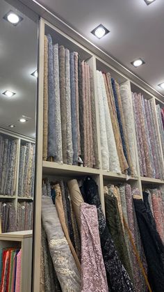 rows of different colored fabrics on shelves in a store with lights above them and floor to ceiling carpeting