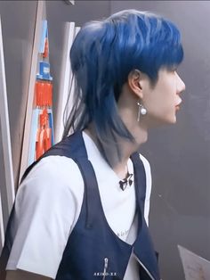 a man with blue hair and suspenders is looking at something on the wall in front of him