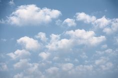 an airplane is flying high in the sky with clouds behind it and blue skies above