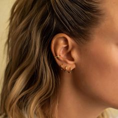 a close up of a woman's ear wearing gold earrings