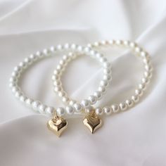 two white bracelets with gold heart charms