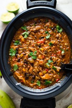 a black pot filled with mexican chicken and tortilla soup next to limes