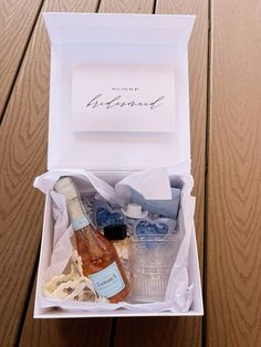 an open box containing two bottles of wine and condiments on a wooden table