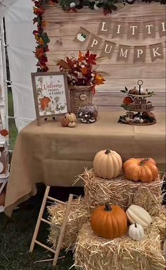 a table with hay and pumpkins on it in front of a sign that says little pumpkin