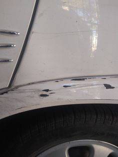 the front end of a white car with black spots on it's paint job