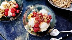 three bowls filled with ice cream, strawberries and crumbled toppings on top of a table