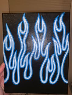 a hand holding up a painting with blue flames on it