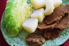 a green plate topped with meat, lettuce and potatoes