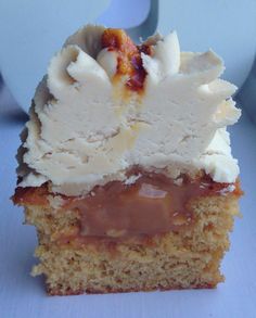 a piece of cake with icing and nuts on top is sitting on a blue surface