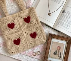 a crocheted bag sitting on top of a bed next to an open book